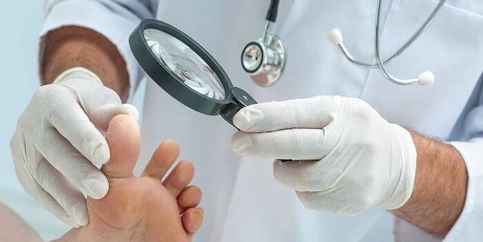 Doctor examining patient's foot with magnifying glass